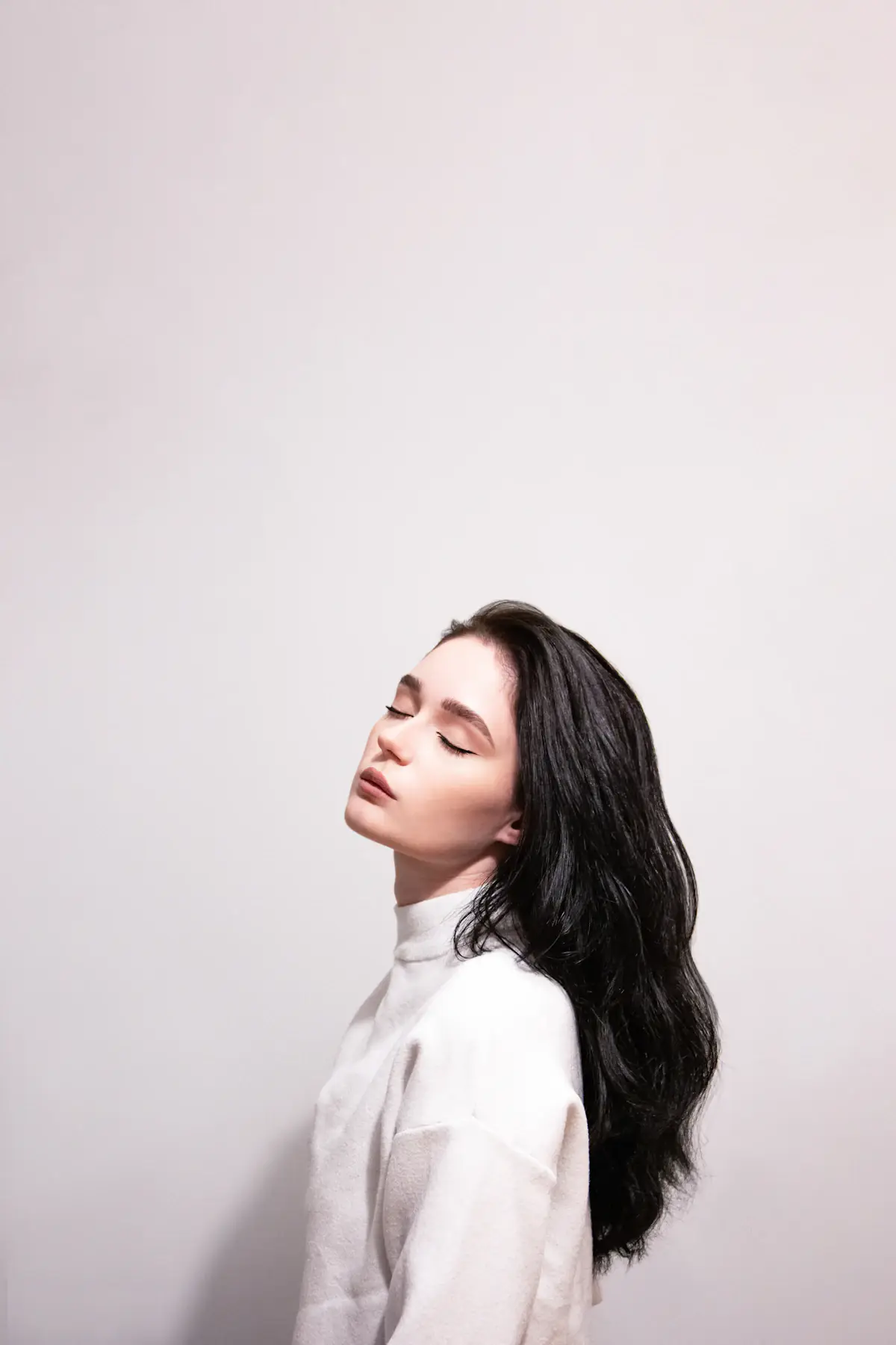 Mulher de perfil, com cabelo escuro, ondulado e comprido