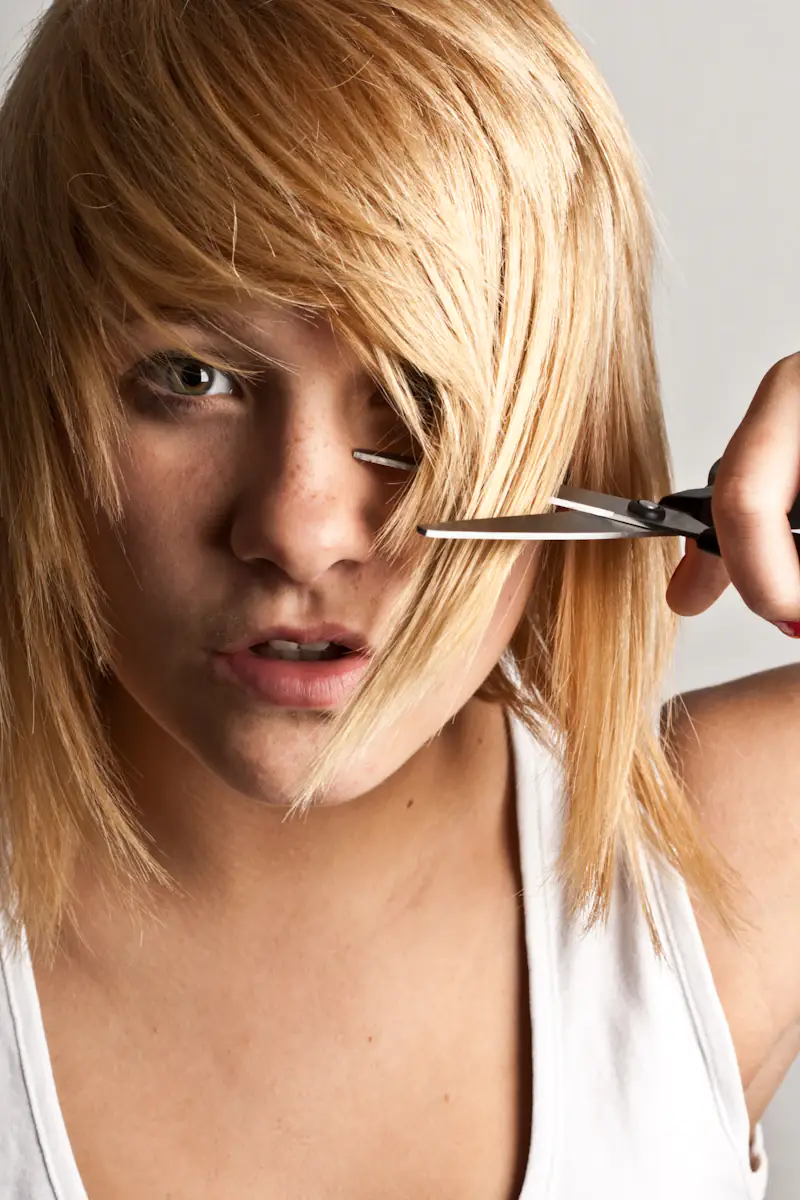 Tesoura cortando a franja de um cabelo loiro